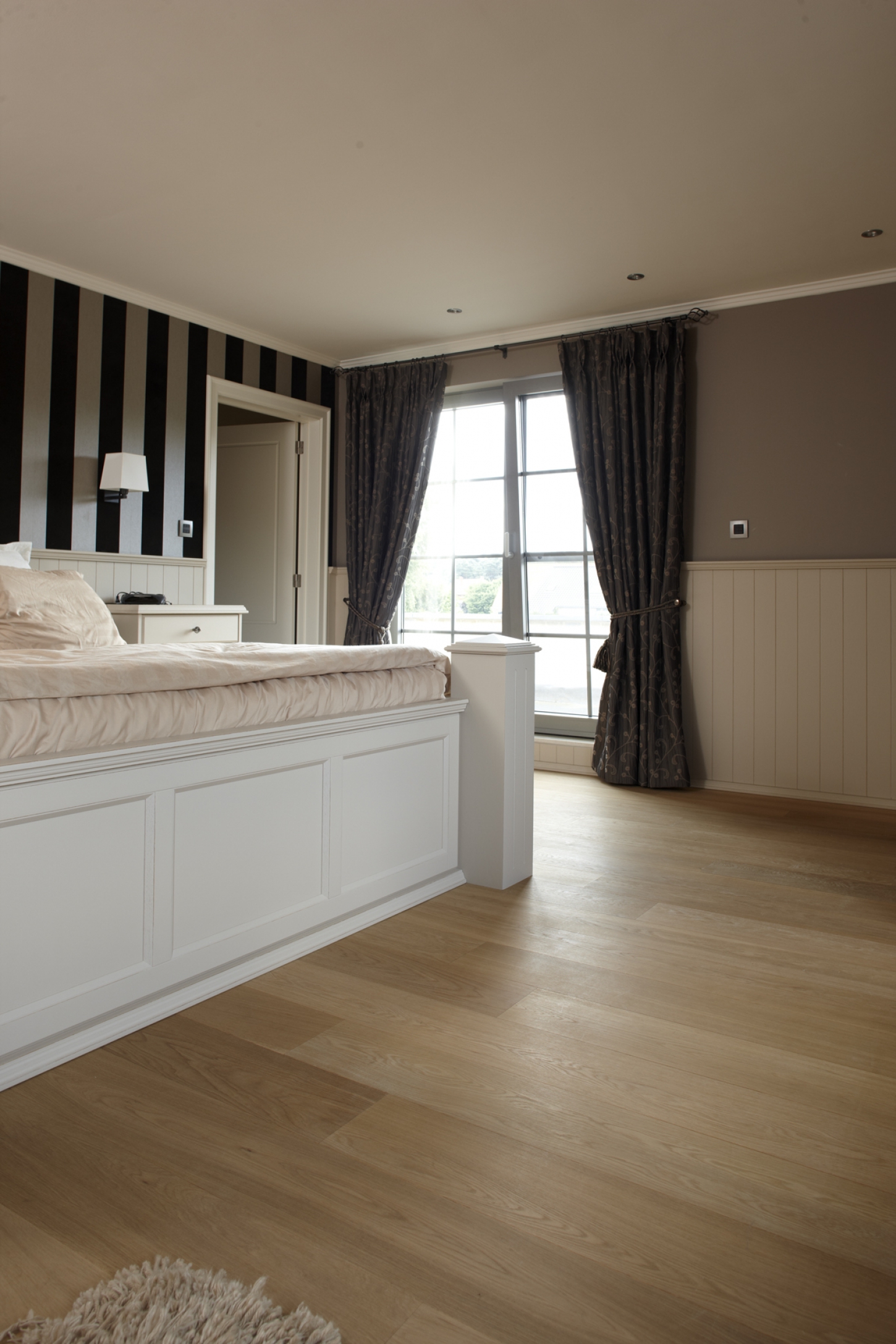 Een slaapkamer met groot bed en een vloer uit parket of laminaat.
