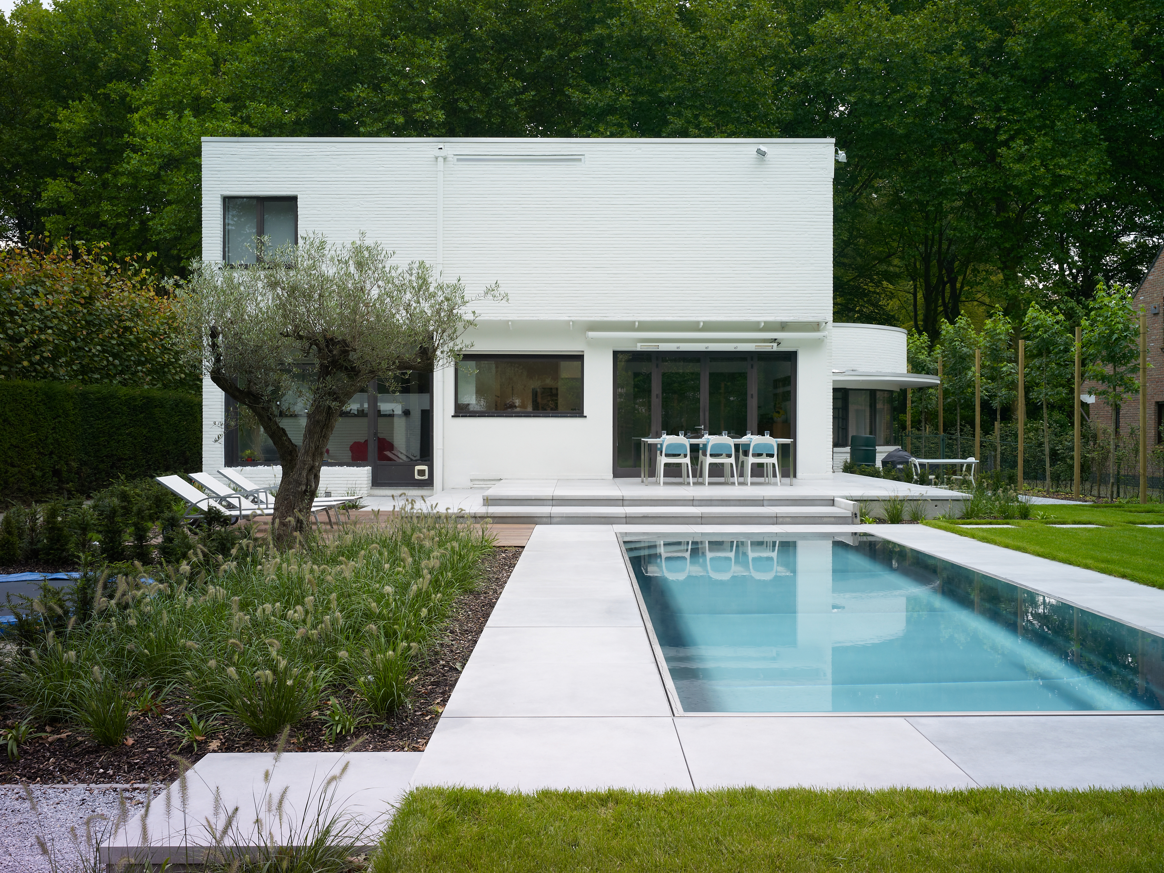 Een moderne, witte villa met zwembad in de tuin. 
