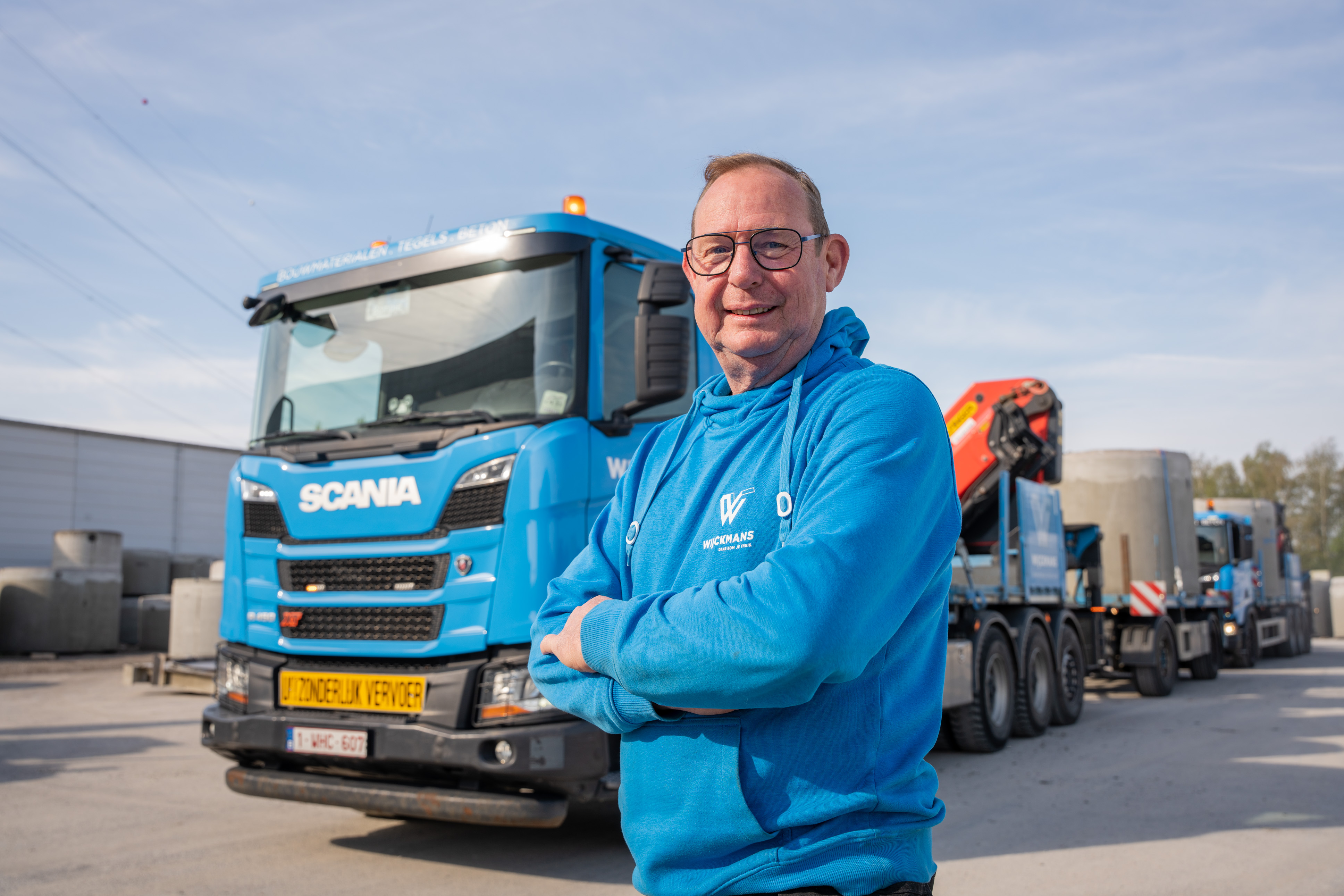 Chauffeur van Wijckmans met armen gekruist bij blauwe camion van Wijckmans.